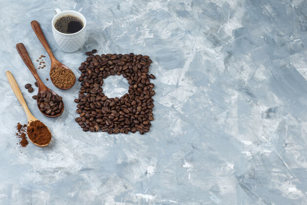 味道一套咖啡豆 速溶咖啡 咖啡粉在木制勺子上 一杯咖啡在浅蓝色大理石背景上高角度视图角度热讨论