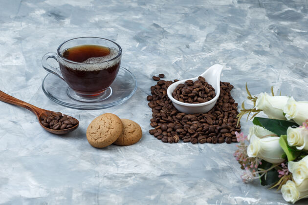 把咖啡豆放在白瓷壶里 放上饼干 咖啡杯 鲜花自然早餐质地