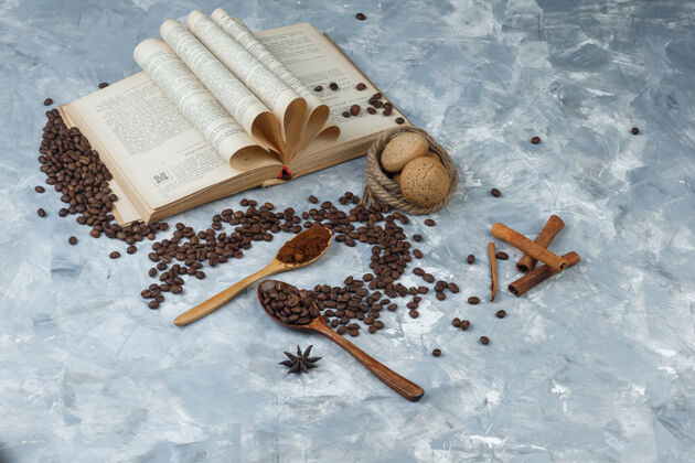 阿拉伯语咖啡豆在一个木制勺子与研磨咖啡 书 香料 饼干高角度看在一个肮脏的灰色背景勺子烤热