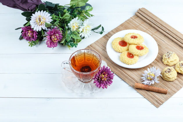 早晨曲奇饼 肉桂放在有花的垫子上 一杯茶放在白色木板背景上高角度观看高餐垫健康