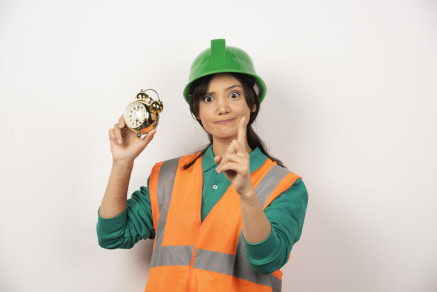 雇员竖起大拇指拿着钟的女员工时钟竖起大拇指建筑工人