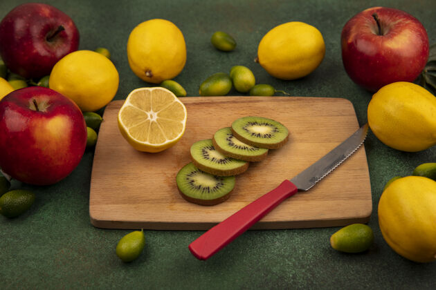 健康新鲜的猕猴桃切片的顶视图在一个木制的菜板上 刀子上有柠檬和彩色的苹果 它们被隔离在一个绿色的表面上热带五颜六色美味