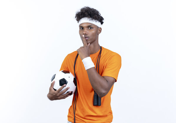 肩膀年轻的美国黑人运动男子戴着头带和腕带持球表示沉默的姿态与跳绳在肩上男人年轻非裔美国人