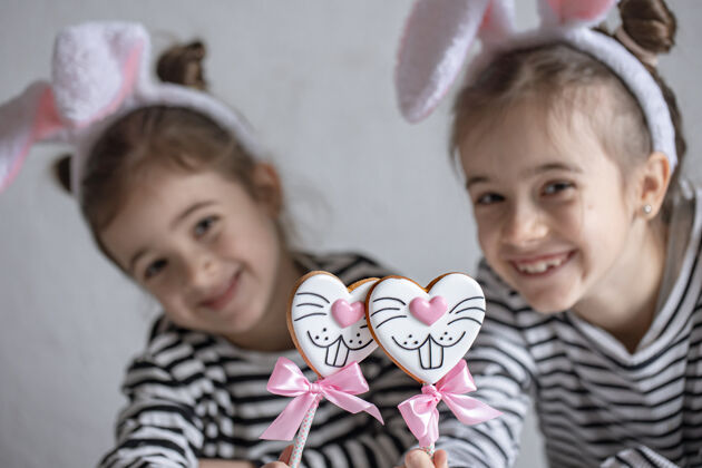 小头上戴着复活节兔子耳朵的小女孩们拿着姜饼饼干食物人甜点