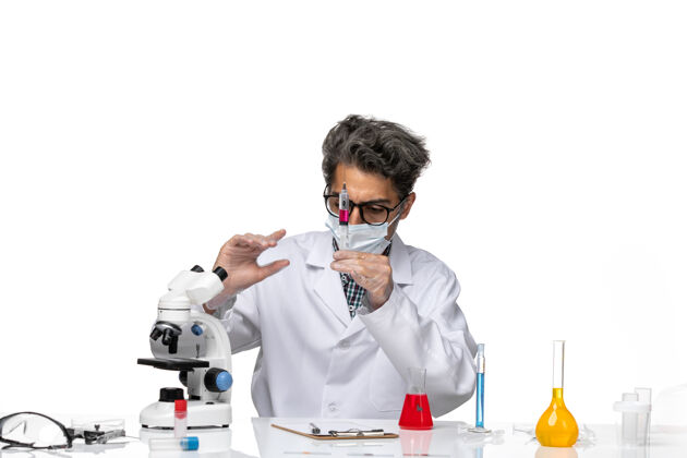 病毒正面图身着白色医疗服的中年科学家用红色溶液填充注射剂面具医学实验室