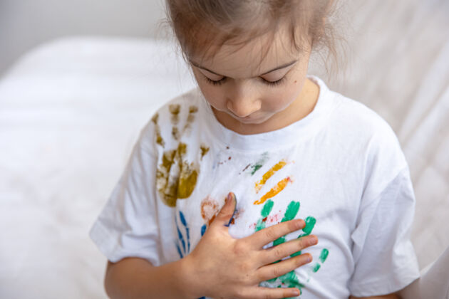 小一个小女孩在t恤上留下了画过的手掌的痕迹孩子们的创造力和艺术微笑艺术品污渍