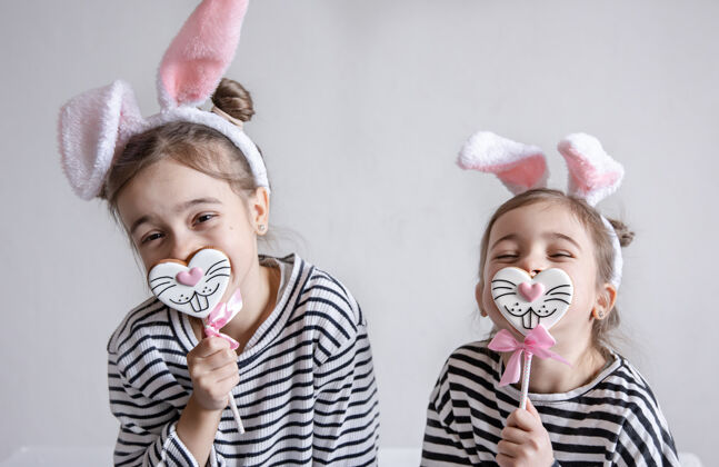 美味两个有趣的小妹妹正以兔子脸的形式与复活节姜饼合影耳朵孩子食物