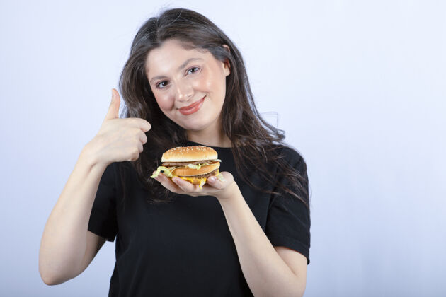 快乐美丽的年轻女子拿着美味的牛肉汉堡 竖起大拇指汉堡食物新鲜