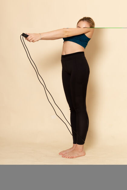 模型正面图穿着运动服的年轻女性正在跳绳练习运动人跳跃