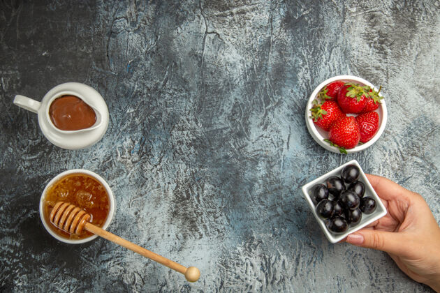 勺子顶视图新鲜草莓与橄榄和蜂蜜在黑暗的表面浆果甜水果勺子新鲜草莓设备
