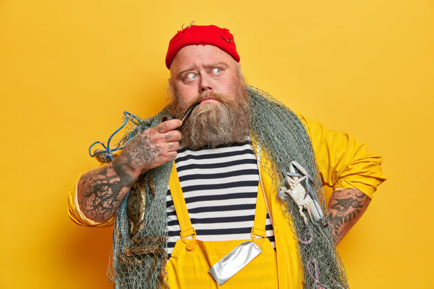 胡须有经验的老胡子水手想第二天在海上 摆姿势渔具 烟斗 穿着工作服 红帽子网男人男性