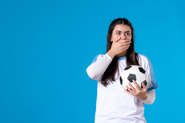 足球前视图：蓝色墙上有足球的年轻女性蓝色球人物