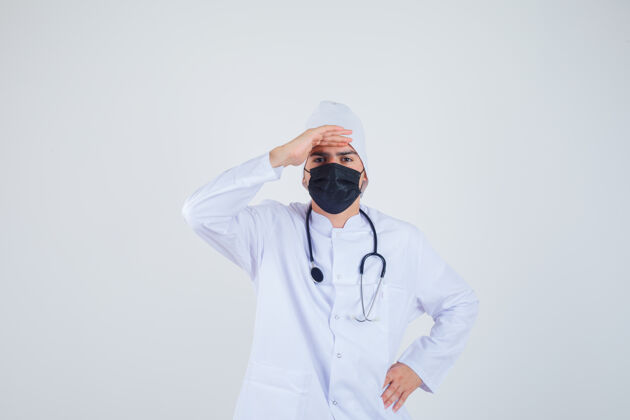 头年轻人头戴白制服 戴着面罩 神色专注地看着远处前视图药专业病人