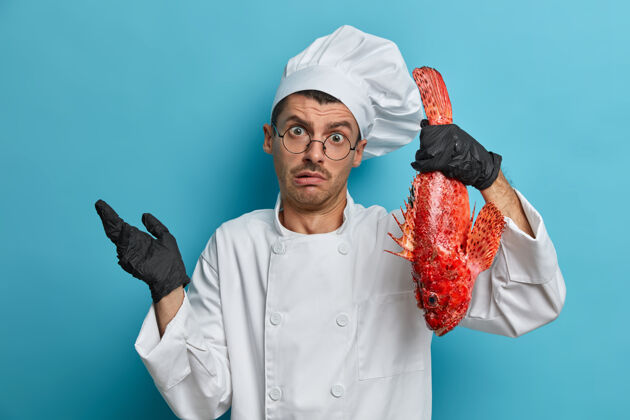 眼镜专业厨师的室内镜头 用鲈鱼做菜 困惑中耸耸肩钓鱼鱼餐厅