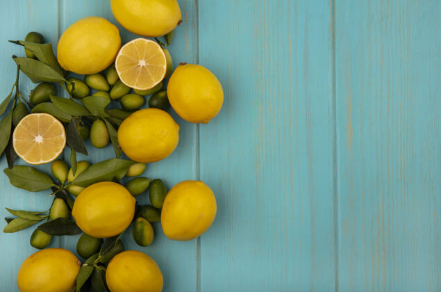 人顶视图绿色和黄色水果 如金盏花和柠檬隔离在一个蓝色的木制墙壁与复制空间景观水果饮食