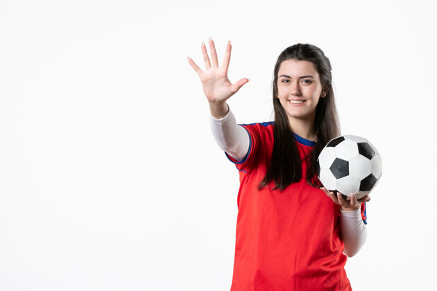 视图前视图穿着运动服的年轻女性 白色墙壁上有足球青年前面球