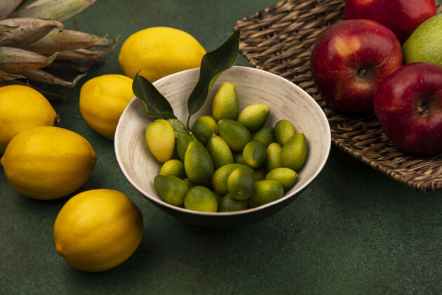 苹果一碗芳香的金盏花的俯视图 柳条托盘上放着新鲜的红苹果 绿色的墙上隔离着柠檬新鲜碗顶部