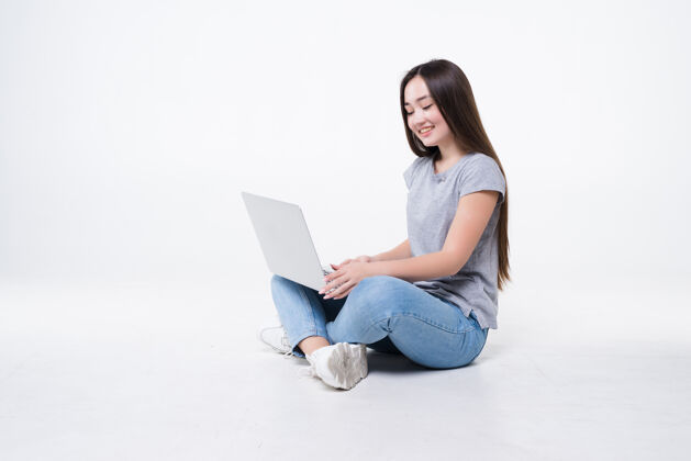 电脑坐在地板上的年轻女子 笔记本电脑被隔离在白墙上自由职业者休闲女性