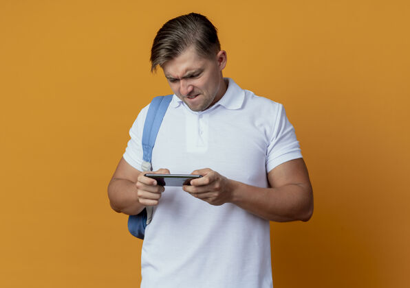 男性紧张的年轻帅气男同学背着书包玩着电话孤零零的放在橘子上橙色背部紧张