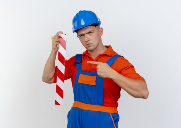 胶带严格年轻的男建筑工人穿着制服 手持安全帽 指着白纸上的胶带男性年轻持有