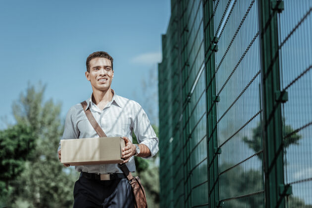 包装本地送货低角度吸引男性快递员携带包裹和行走盒子城市服务