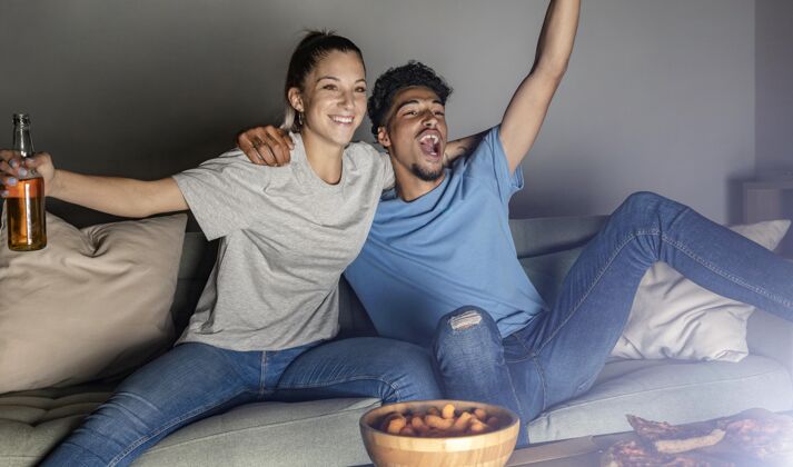 食物男人和女人在家里喝着啤酒和零食 一边看电视一边欢呼女人足球比赛比赛