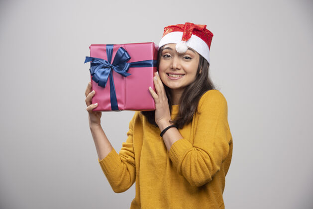 模型带着圣诞礼物的戴着圣诞老人红帽子的微笑女人女性女孩礼品盒