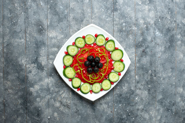 盘子顶视图切片黄瓜和橄榄在灰色桌子沙拉蔬菜色维生素健康饮食盘中食物比萨饼晚餐