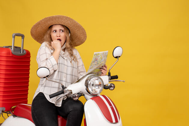 感情顶视图年轻女子戴着帽子 坐在摩托车上 拿着地图 对黄色感到惊讶坐人举行