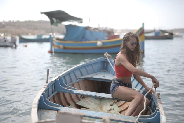 女性白昼阳光下 年轻迷人的女子坐在水面上的木船上旅行水海