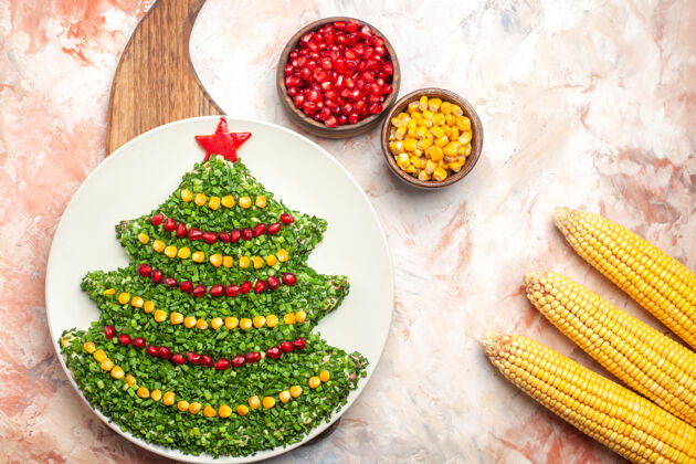 树顶视图美味的新年树形蔬菜沙拉 石榴和玉米在灯光背景下圣诞节食物晚餐