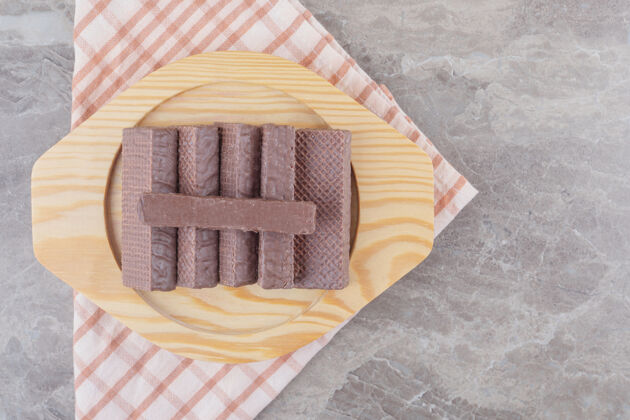 甜点把涂有巧克力的薄饼放在大理石上的木盘上美味零食口感