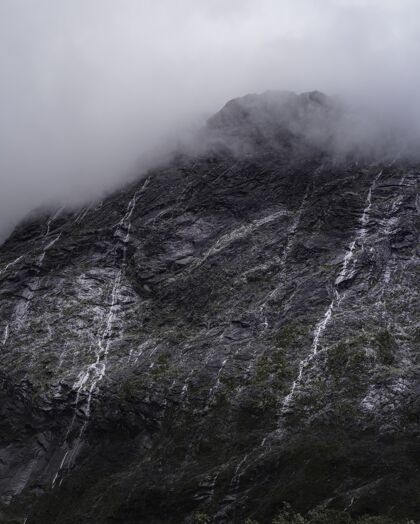 自然大雾天气下 一座雄伟的山峰和小瀑布的垂直拍摄徒步旅行奇迹全景