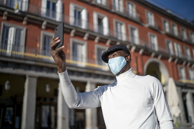 民族特写镜头一个黑人男子拿着他的手机穿着高领概念的新常态设备年轻病毒
