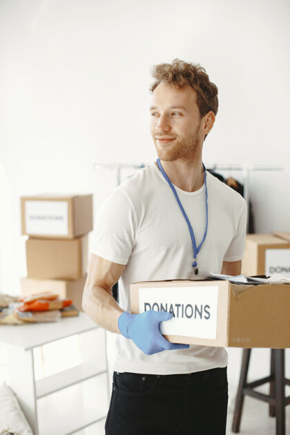 助理志愿者从捐款中收集东西男人用东西包装盒子男人比较捐赠室内成人问题