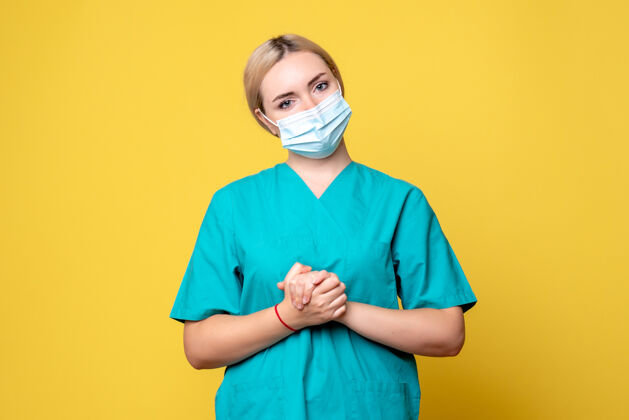 人物黄色墙壁上穿着医用衬衫和面罩的年轻女医生的正视图衬衫人物护士