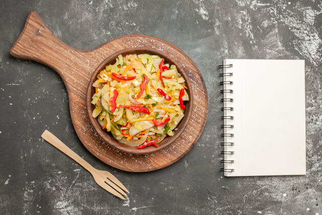 胡椒顶部特写查看沙拉蔬菜沙拉在砧板旁边的叉子笔记本碗蔬菜食物