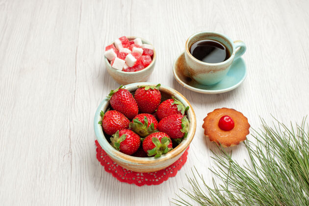 桌子前视小蛋糕上的水果和一杯茶的白色办公桌水果蛋糕茶甜点食品农产品浆果