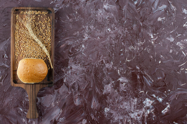 棕色一块用新鲜的白面包做成的木板 背景光是小麦穗新鲜面包硬皮