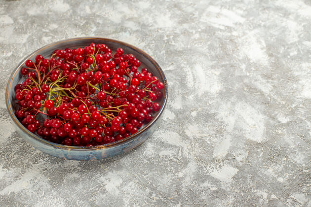 轻前视图新鲜的红色小红莓放在托盘里 浅白的桌上 浆果的颜色是野生的红色可食用水果食品正面