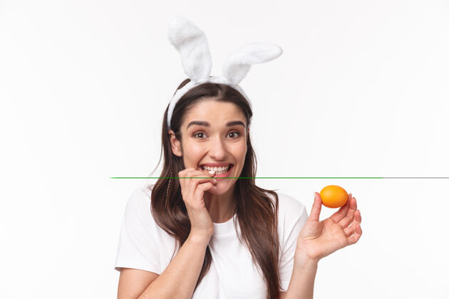 年轻可爱的年轻女子在兔子耳朵里拿着彩蛋微笑商业节日