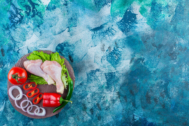 板胡椒 洋葱圈 西红柿 生菜和鸡腿放在一块板上 蓝色背景美味环生菜
