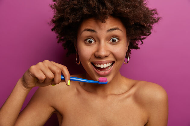 肩膀卷发女人把牙刷握在嘴边 关心个人卫生牙刷光滑抱着