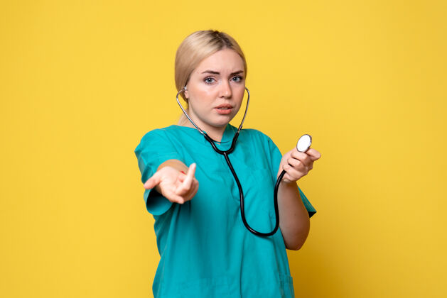 医疗黄色墙壁上穿着带听诊器的医用衬衫的女医生的正视图正面医疗器械听诊器