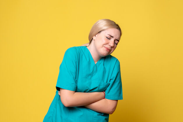 衬衫黄色墙壁上 年轻女医生穿着医用衬衫 胃痛难忍前面护士肖像