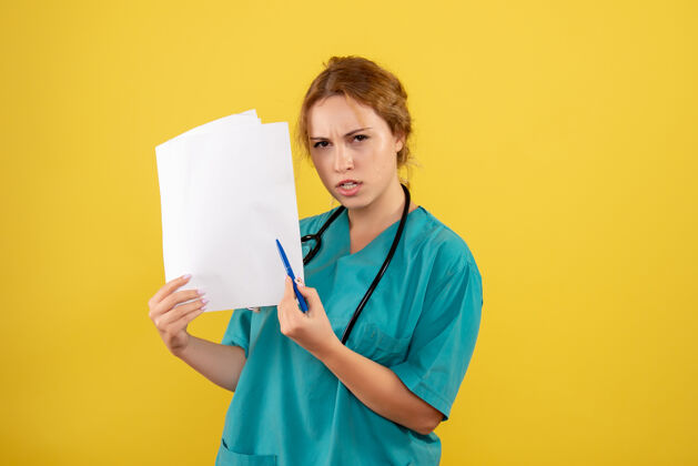 医学黄墙上穿着医疗服的女医生手持分析图女医生医学分析