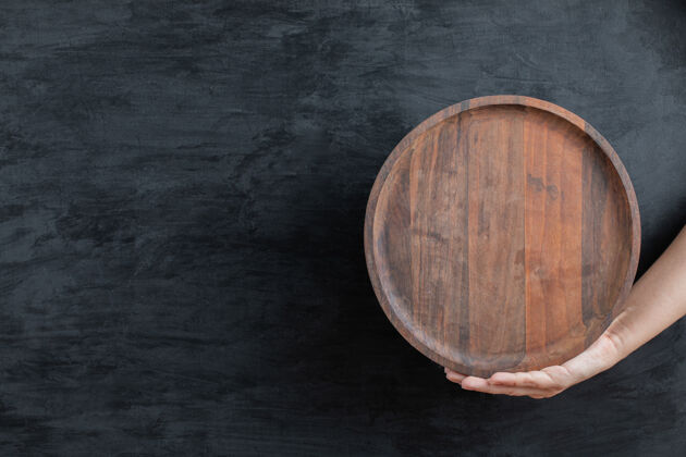 健康用手拿着一个圆形的木盘传统餐厅餐具