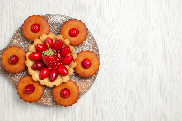 草莓白色桌面上有美味的奶油蛋糕和水果花束甜点成熟