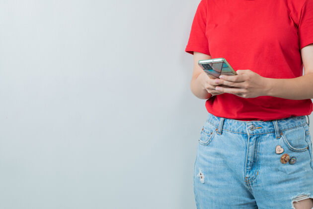 女人穿着红衫的年轻女孩手里拿着一部银色的智能手机服装智能女性