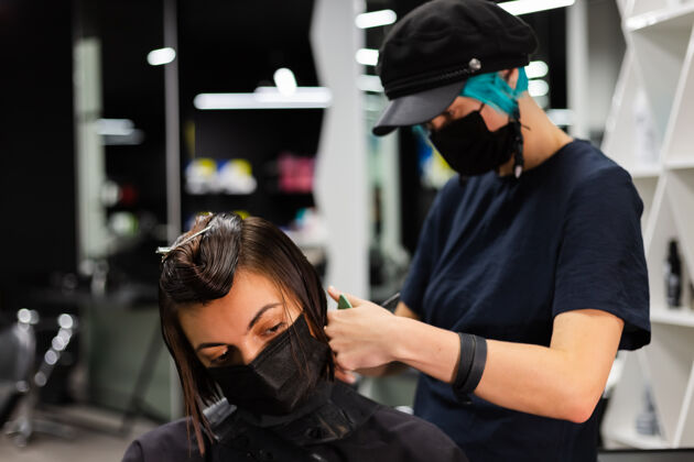 发型师一个专业的女理发师给客户理发这个女孩戴着面具坐在美容院里理发师发廊护理